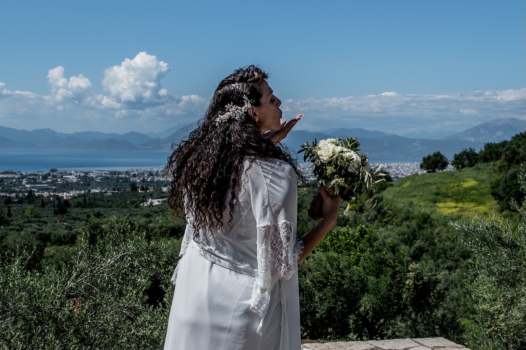 Νύφη με φόντο ελληνικό τοπίο και θέα στη θάλασσα.